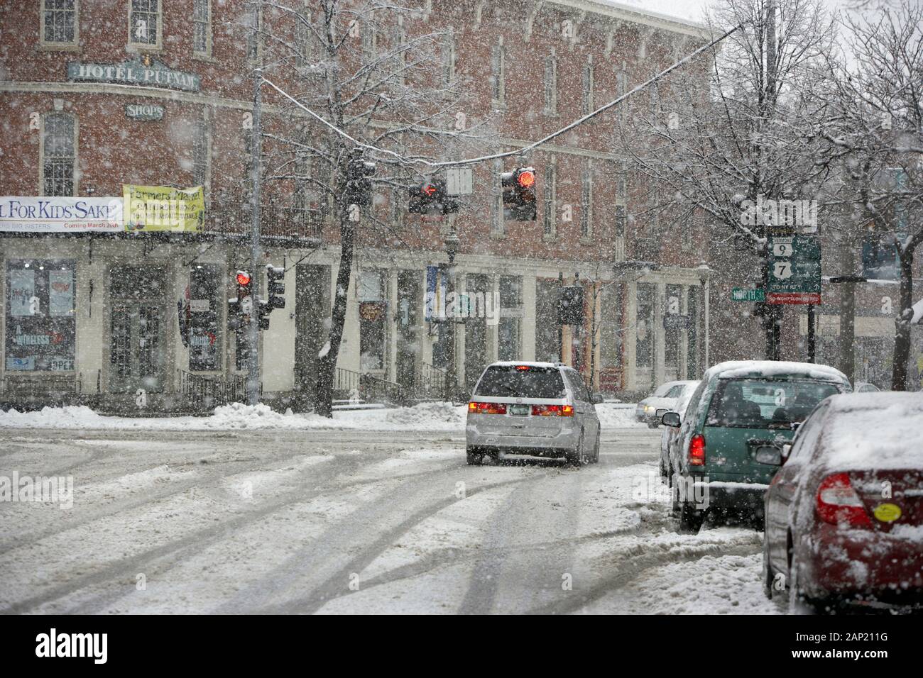 Il traffico su una coperta di neve suburban street durante una tempesta di neve Foto Stock