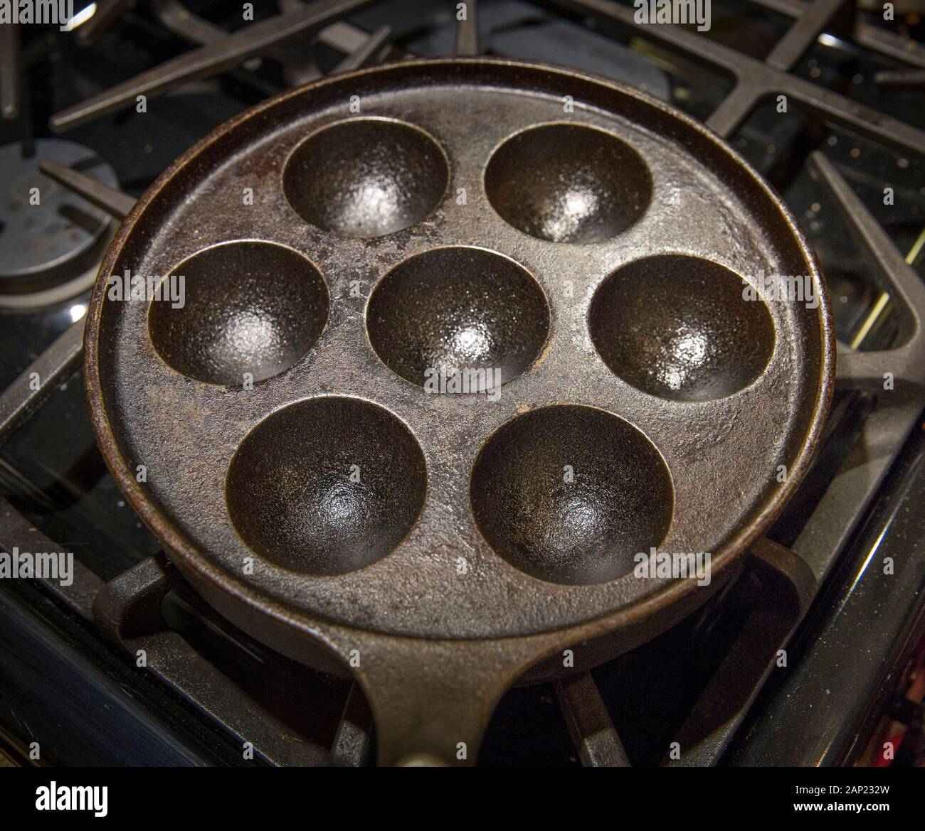 Una cucina ingrassati in ghisa padella di cottura utilizzati per realizzare i pancake danese chiamato Aebleskiver Foto Stock