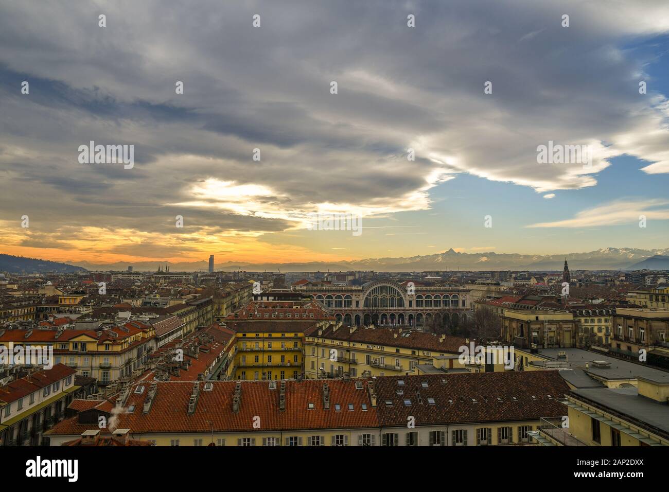 Vista sui tetti di Torino con la stazione ferroviaria di porta Nuova e la catena montuosa delle Alpi Cotziane con picco Monviso in background al tramonto, Piemonte, Italia Foto Stock