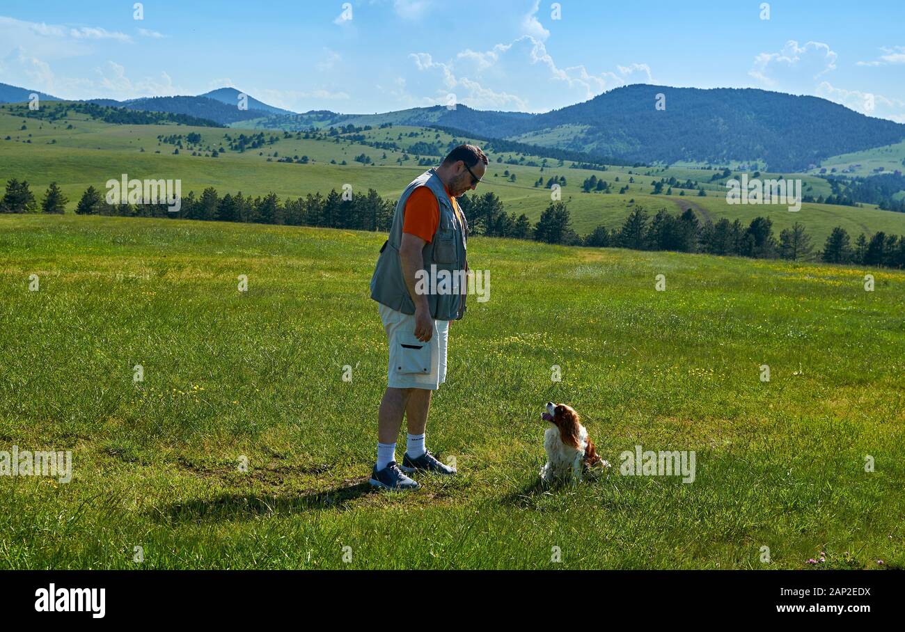 Uomo e cane in un meraviglioso paesaggio di montagna in primavera Foto Stock