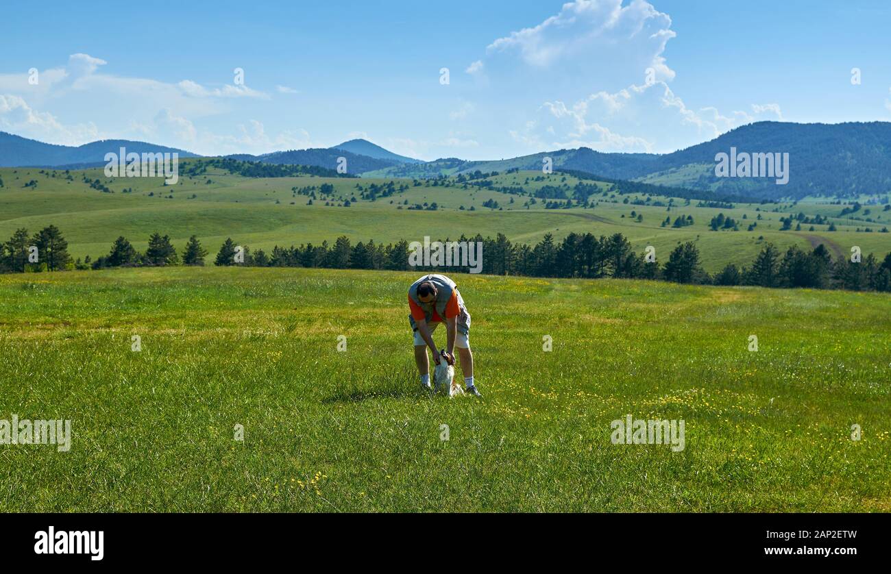 Uomo e cane in un meraviglioso paesaggio di montagna in primavera Foto Stock