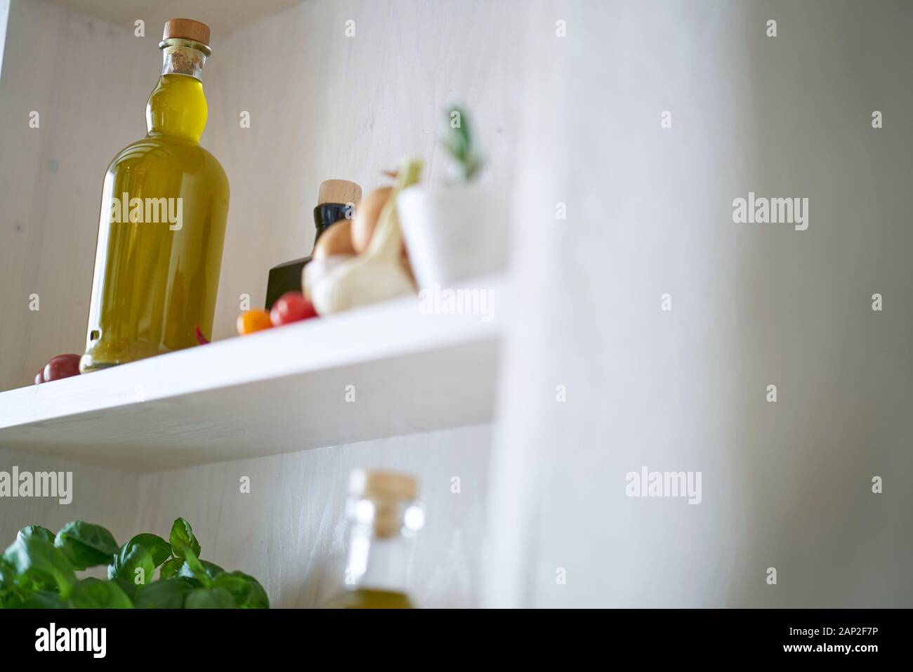 cappelliera cucina ripiano olio d'oliva bottiglia di prezzemolo in stile mediterraneo, verde giallo rosso vegetale vegetariano in sole estate sensazione, copia spazio Foto Stock