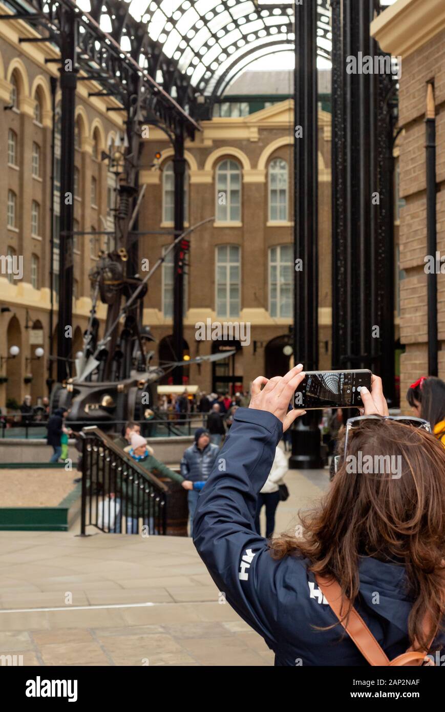 Una ragazza turistica che scatta foto con lo smartphone alla Hay's Galleria sulla South Bank, Londra, Regno Unito Foto Stock