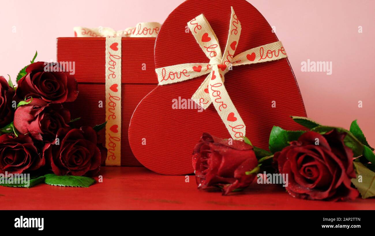 Happy regali di San Valentino e rose rosse sul rosso e sfondo rosa, con copia negativo dello spazio. Foto Stock