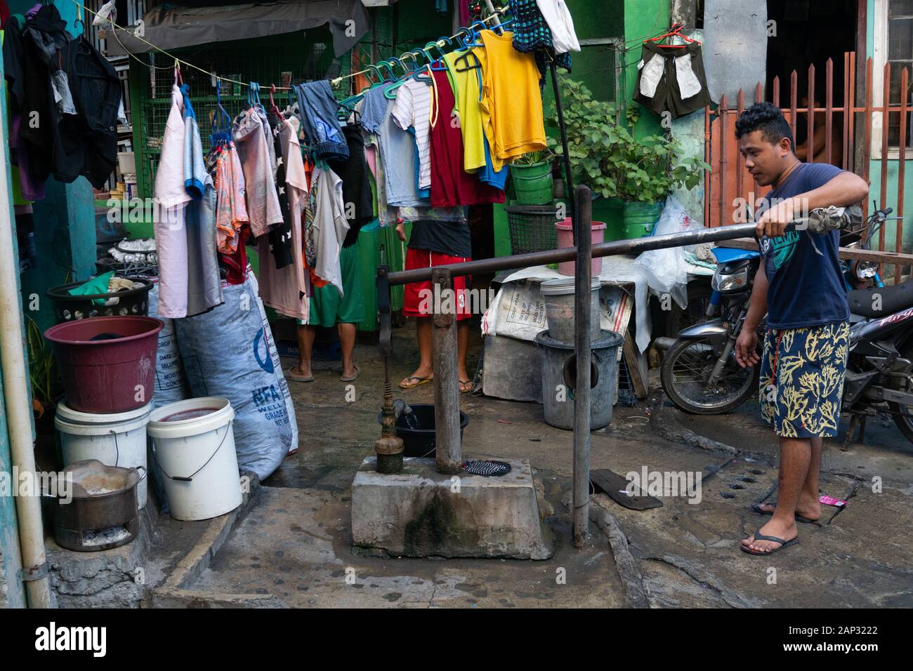 Un uomo entro una comunità povera di Cebu City,utilizza una pompa manuale per sollevare acqua che sarà utilizzata ai fini del lavaggio soltanto. Foto Stock