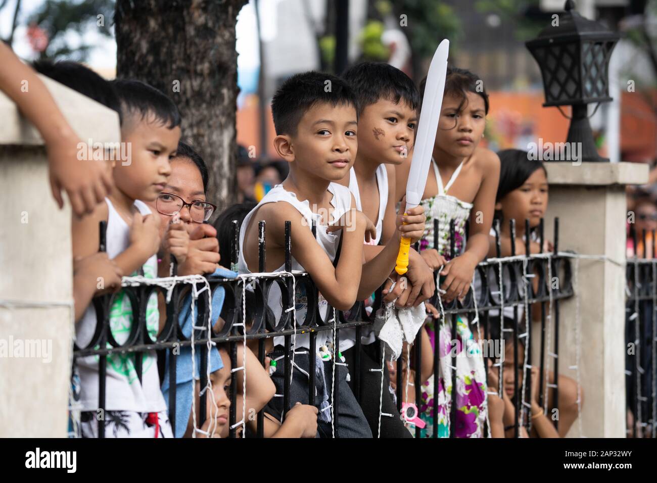 Bambini filippini a guardare il Sinulog Street Parade dietro ringhiere in ferro,Cebu City, Filippine Foto Stock