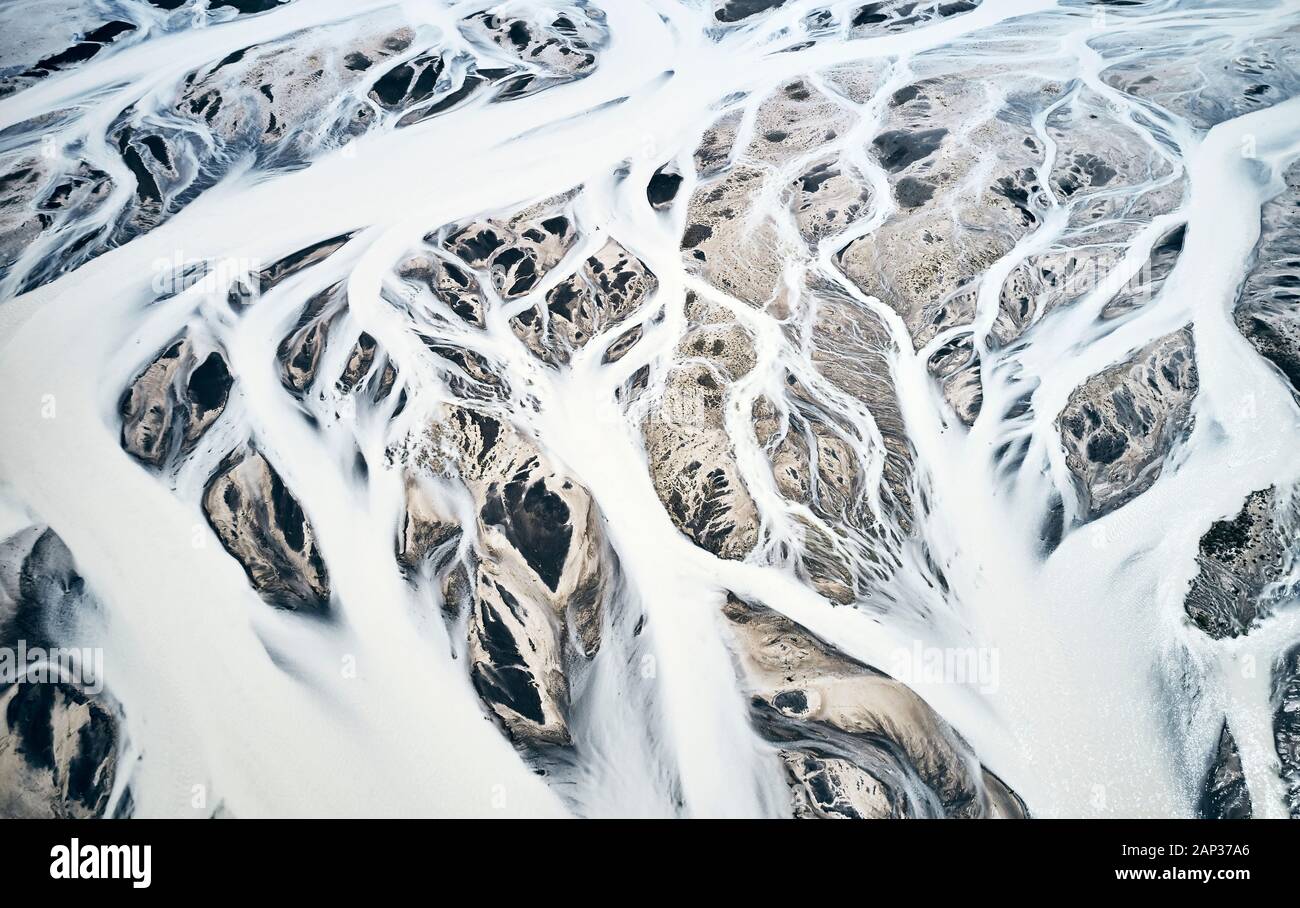 Vista superiore della neve flussi rivestito di taglio attraverso circostante paesaggio montuoso in potenti linee fluide Foto Stock