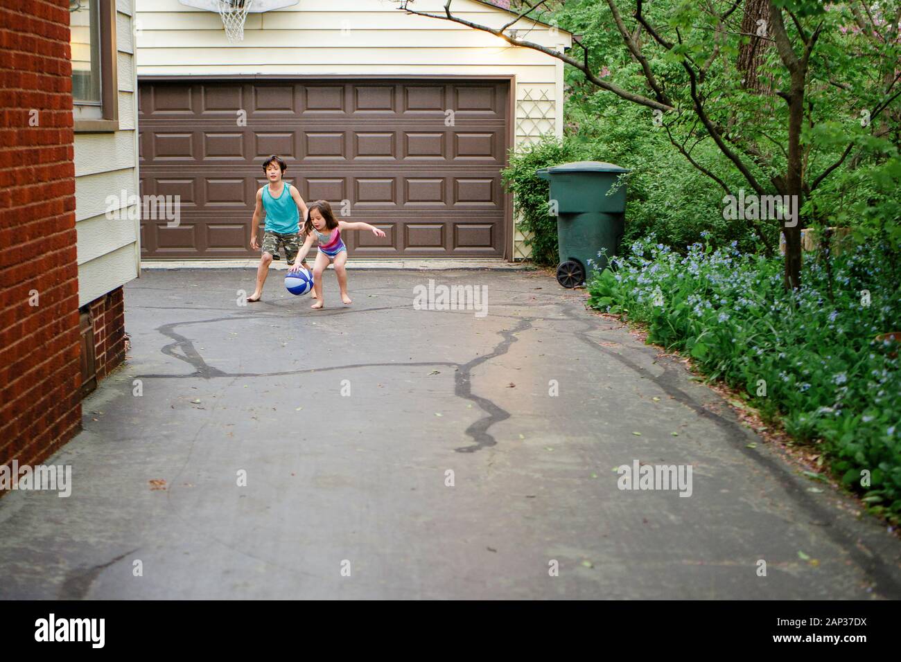 Due bambini piccoli a piedi nudi giocano insieme a basket nel vialetto Foto Stock