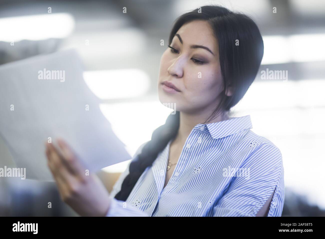 giovane donna asiatica con carta in un concentrato di ufficio Foto Stock