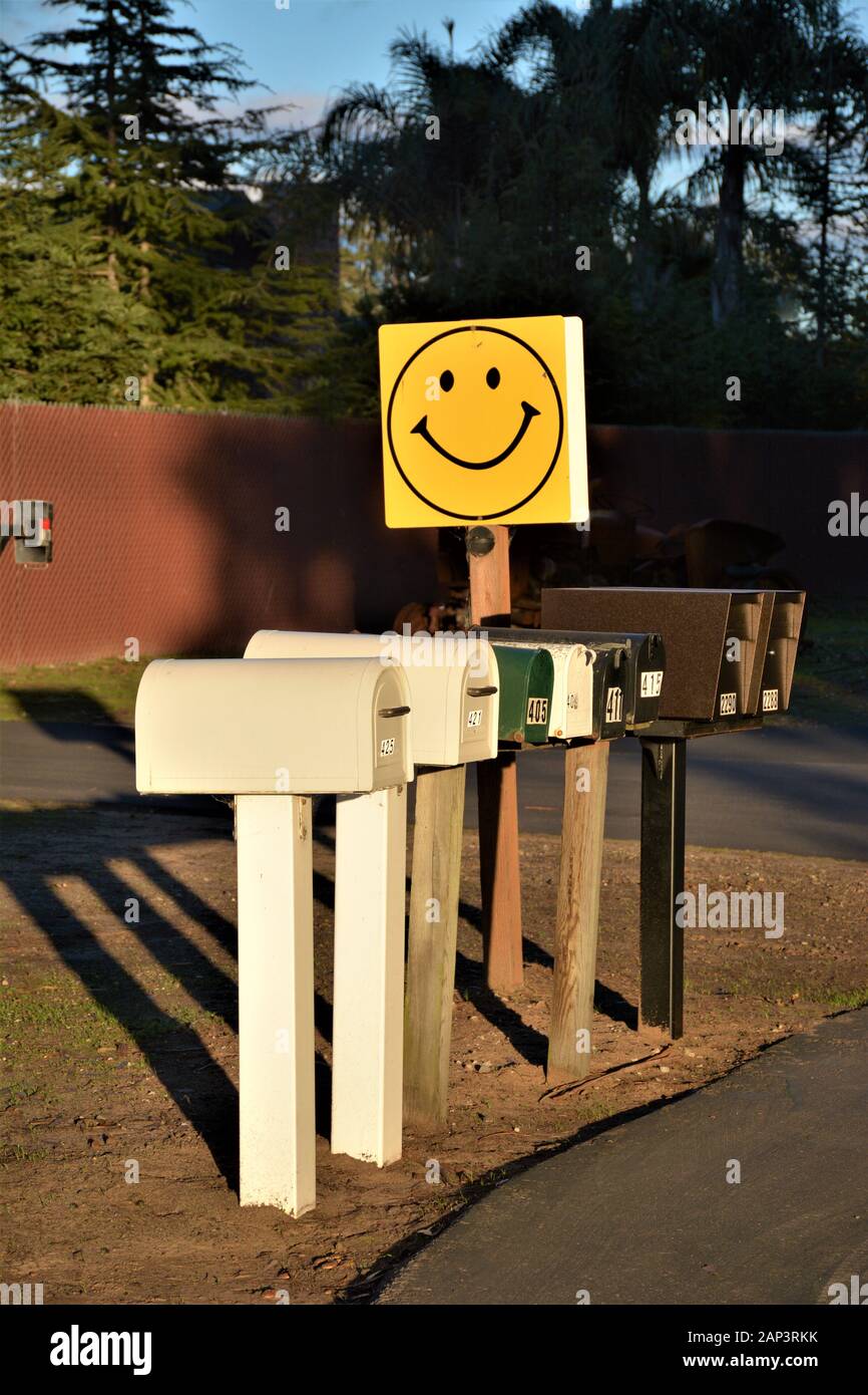 Gruppo di caselle postali per consegna giornaliera con faccia felice su di loro in strada nella zona rurale della CA centrale Foto Stock