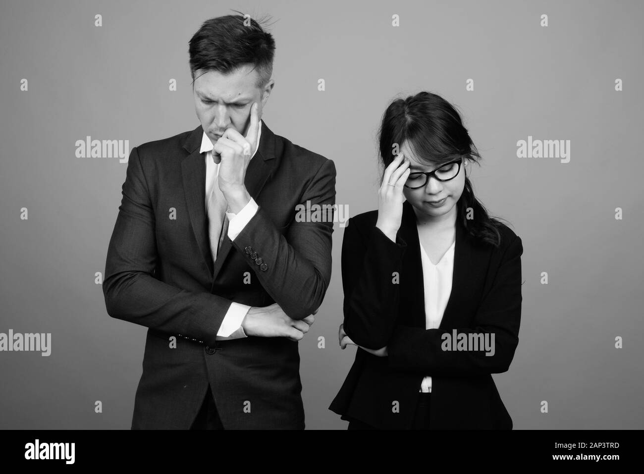 Giovane coppia multietnica di affari che lavora insieme su sfondo grigio Foto Stock