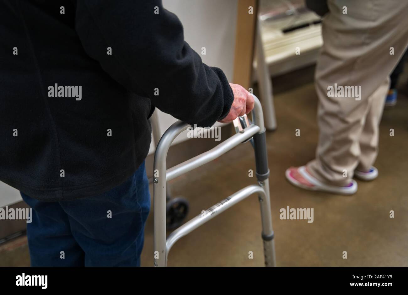 Walker utilizzato da una donna anziana in una struttura interna. Foto Stock