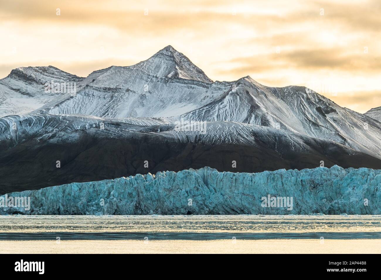 montagna ghiacciata, ghiacciaio blu, cielo giallo - tremendo paesaggio artico Foto Stock