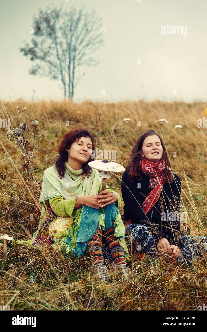 Due ragazze su una collina con funghi in mano. Foto Stock