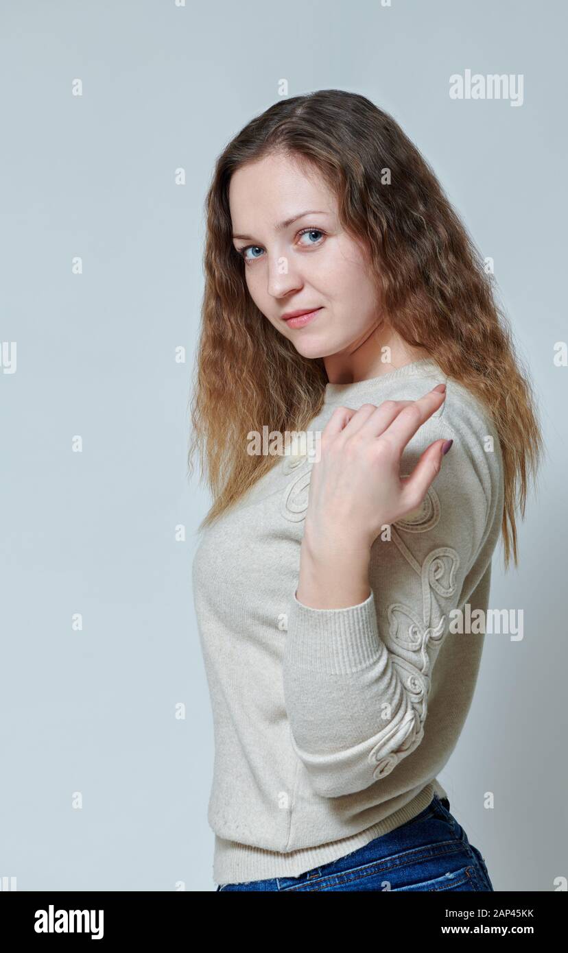 Giovane donna in posa davanti alla telecamera con capelli ricci Foto Stock