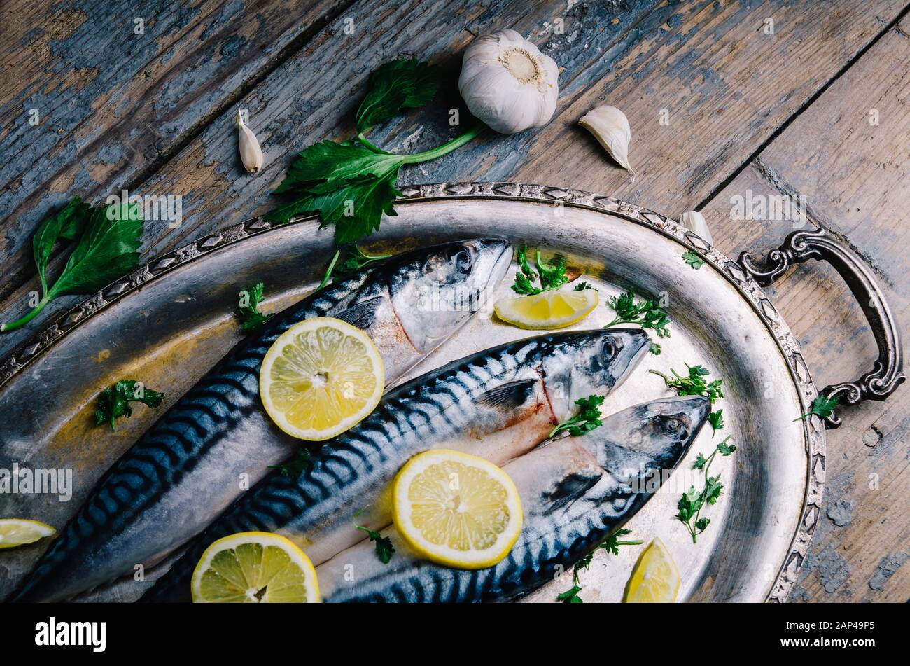 Pesce sgombro fresco con limone e spezie servito su piatto d'argento dall'alto. Piatti di pesce fatti in casa cucina ricetta. Alimenti sani per la dieta preparati per il pranzo Foto Stock