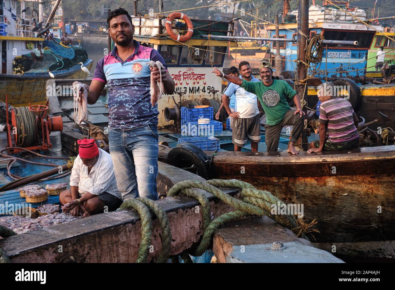 Un pescatore a Sassoon Docks, un porto di pescatori nella zona di Colaba, Mumbai, India, che tiene in mano il calamaro Foto Stock