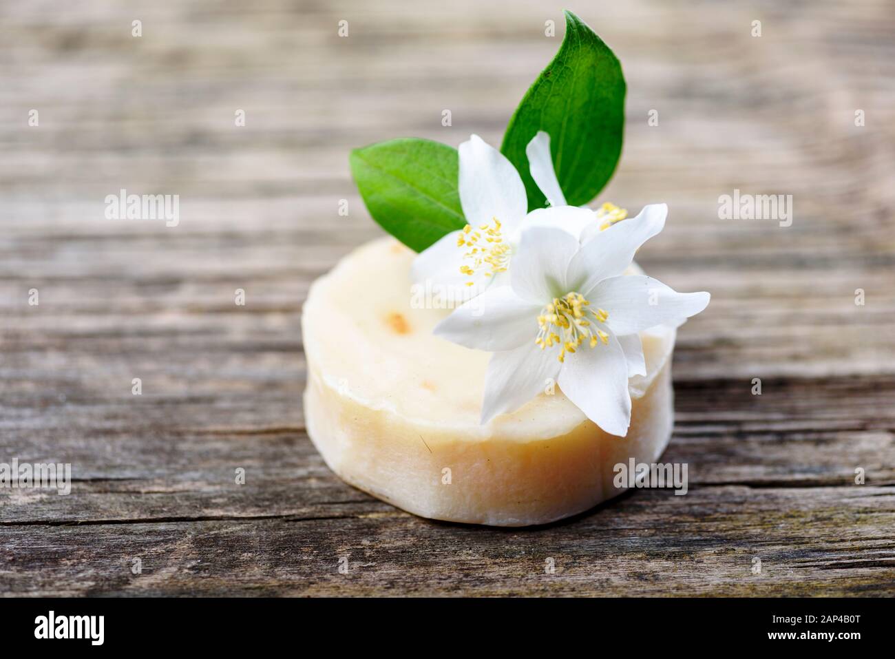 Primo piano di sapone naturale biologico fatto a mano con latte di capra e erbe di fiori di gelsomino su tavola di legno vintage. Cosmetici per la cura della pelle. Spa, benessere, aromatica Foto Stock