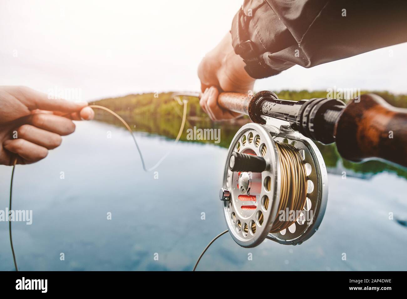 Bobina di corda da pesca del mosca, mano dell'uomo che tiene la canna Foto Stock