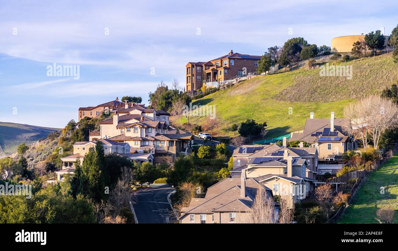 Quartiere residenziale con multilevel case unifamiliari, costruito su una zona collinare; serbatoio di acqua visibile sulla parte superiore della collina; Hayward, East San Francesco Foto Stock
