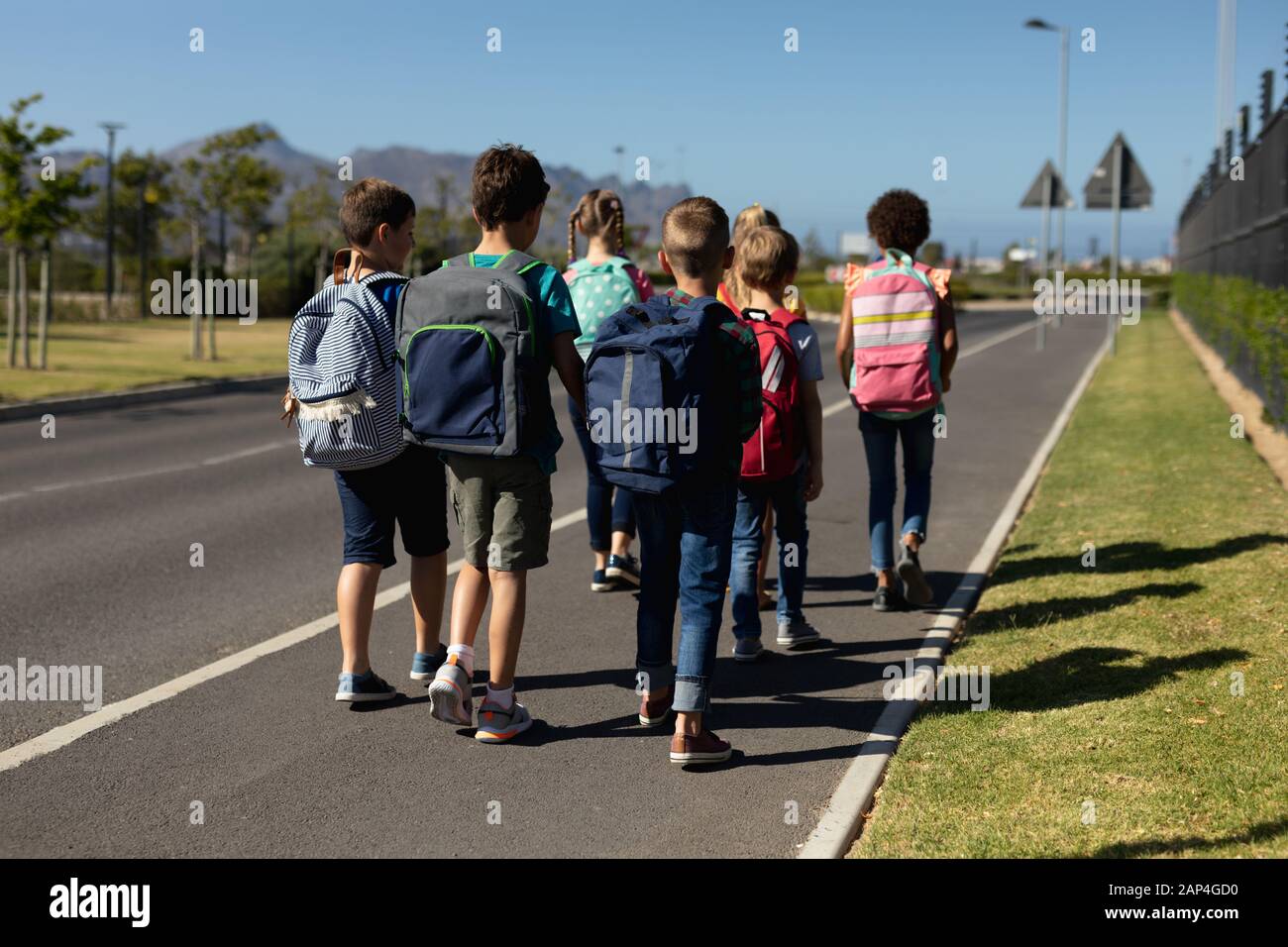 Gruppo di alunni delle scuole elementari che camminano lungo una strada Foto Stock