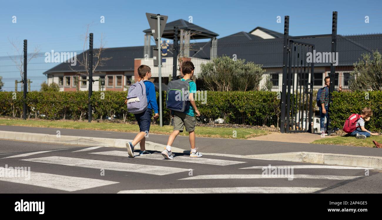 Due scolari che attraversano la strada su un passaggio pedonale Foto Stock