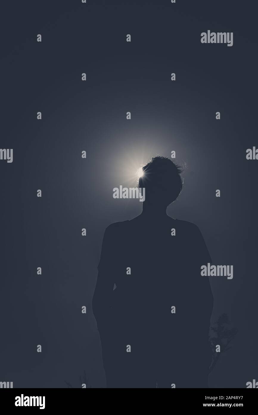 Silhouette di una persona con sole dietro che causa l'effetto eclissi del sole. Nessun colore. Immagine scura e ad angolo basso di qualcuno irriconoscibile. Foto Stock