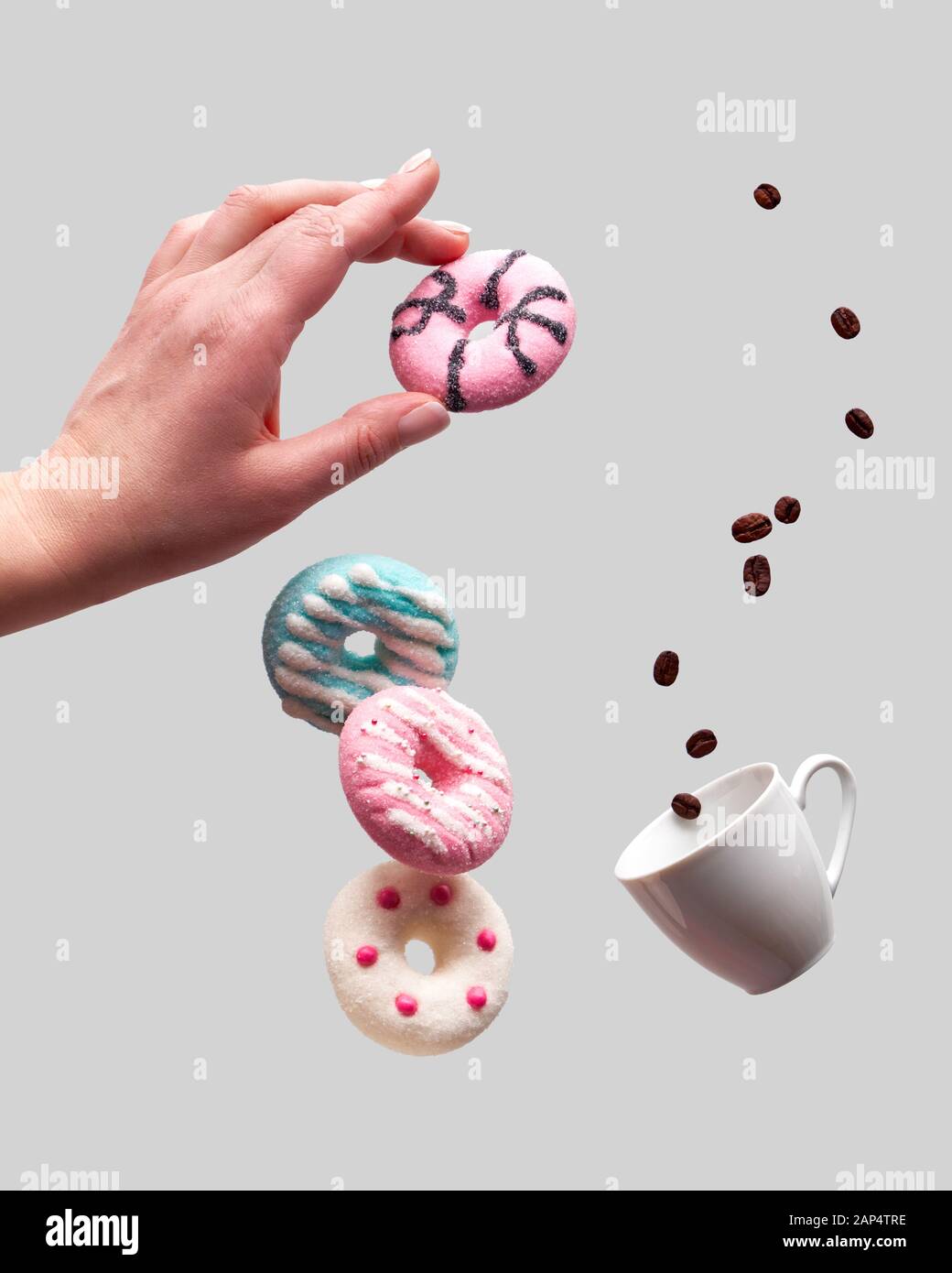 San Valentino concetto, levitazione di ciambelle al di sopra del cuore ciotola sagomata. I chicchi di caffè volare in tazzina. Tenere in mano ciambella rosa. Background creativo Foto Stock