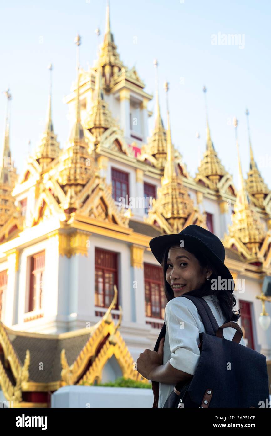 Capelli ondulati donna in black hat visitare il bellissimo tempio in bianco e dorato. Foto Stock
