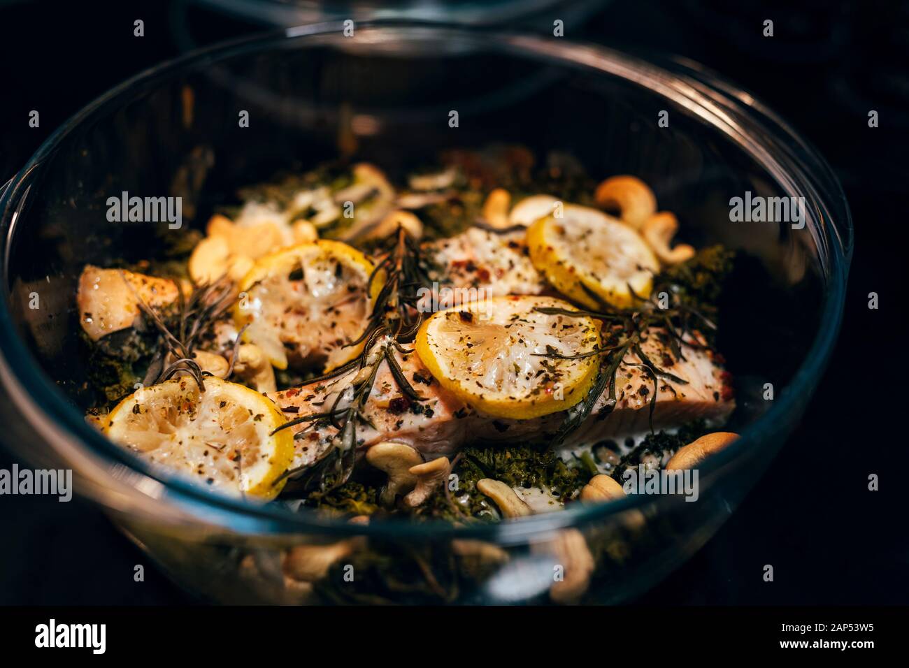 Close up foto di pronto il piatto con il pesce in vasi di vetro con limone e rosmarino noci di anacardio in forno Foto Stock