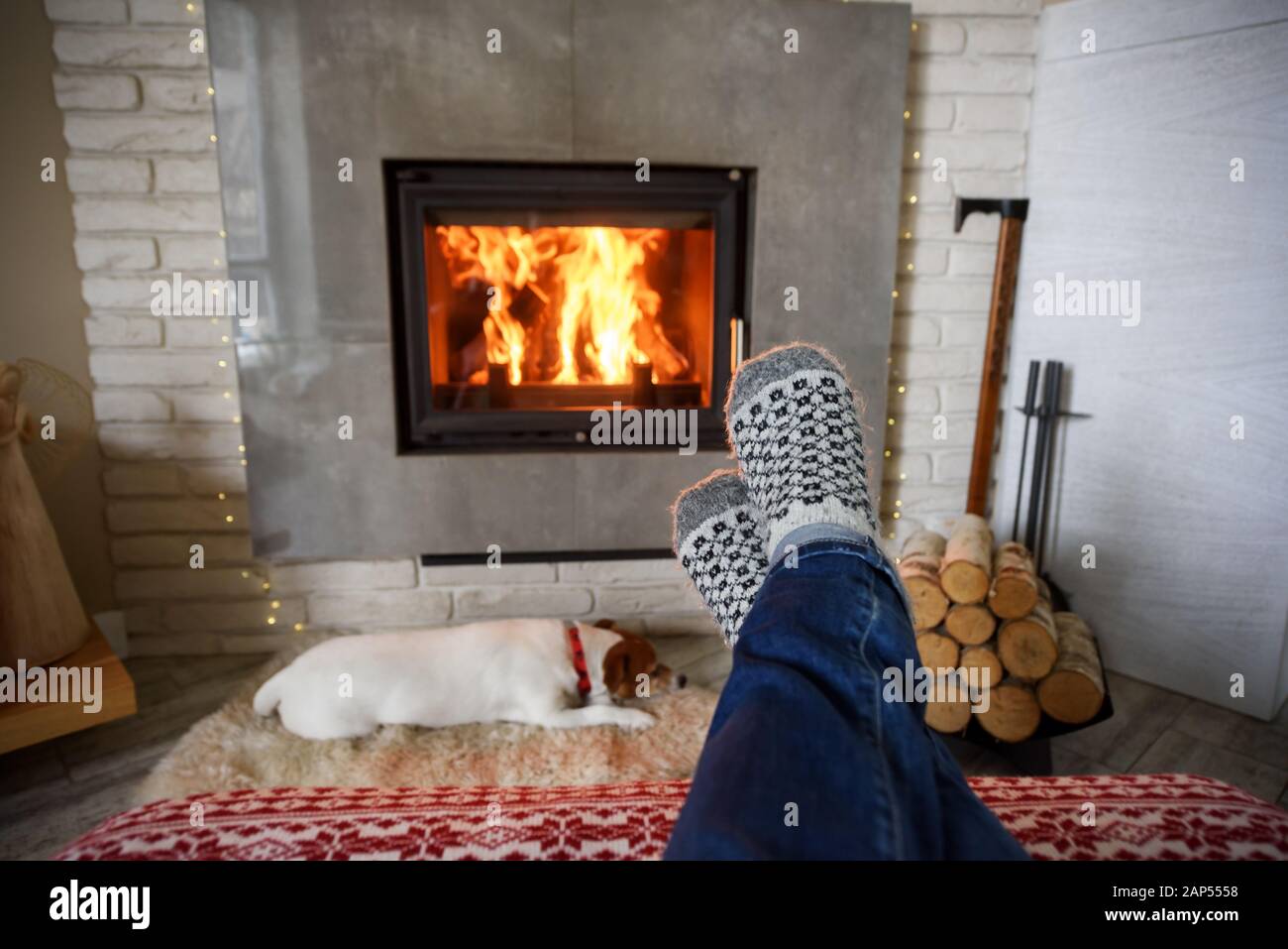 Concetto di Hygge con gambe di uomo in calze di lana vicino al caminetto Foto Stock