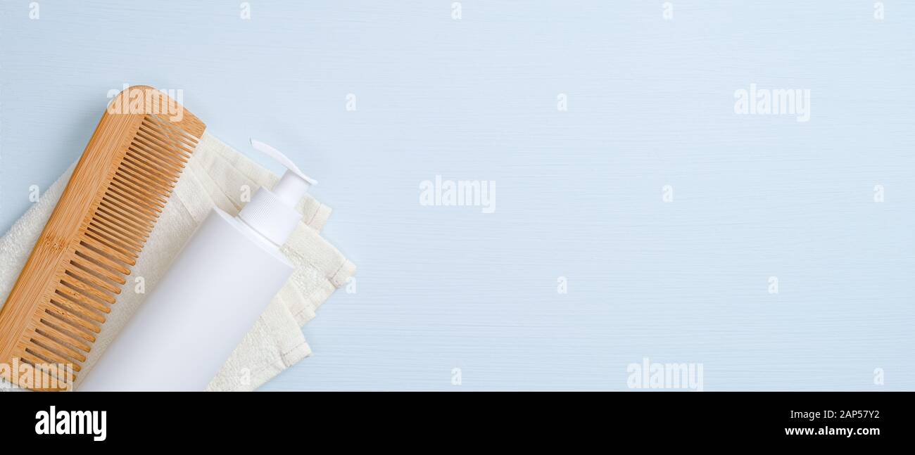 Cura dei capelli concetto di design. SPA pompa cosmetici confezionamento delle bottiglie in legno Pettine per capelli, asciugamano bianco su sfondo blu. Minimalista prodotto cosmetico mo Foto Stock