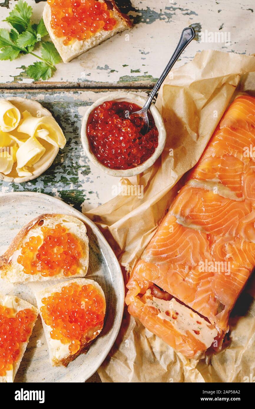 Rosso Salmone caviale in un recipiente e sul pane di grano, Terrina di salmone serviti con burro sulla piastra in ceramica su un vecchio tavolo di legno. Laici piana, spazio Foto Stock