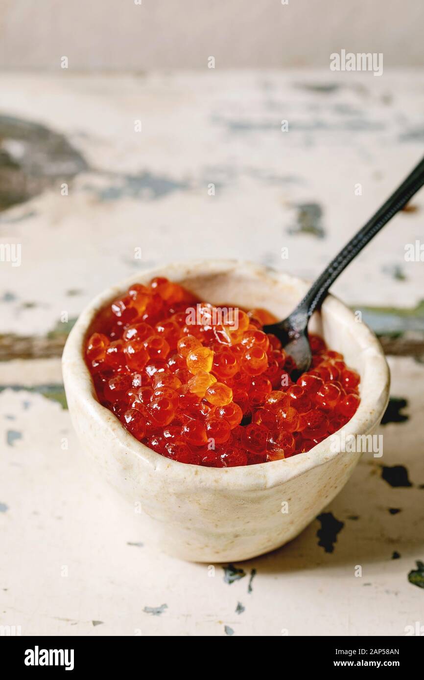 Rosso Salmone caviale in vaso in ceramica con cucchiaino sul vecchio tavolo in legno. In stile rustico, spazio di copia Foto Stock