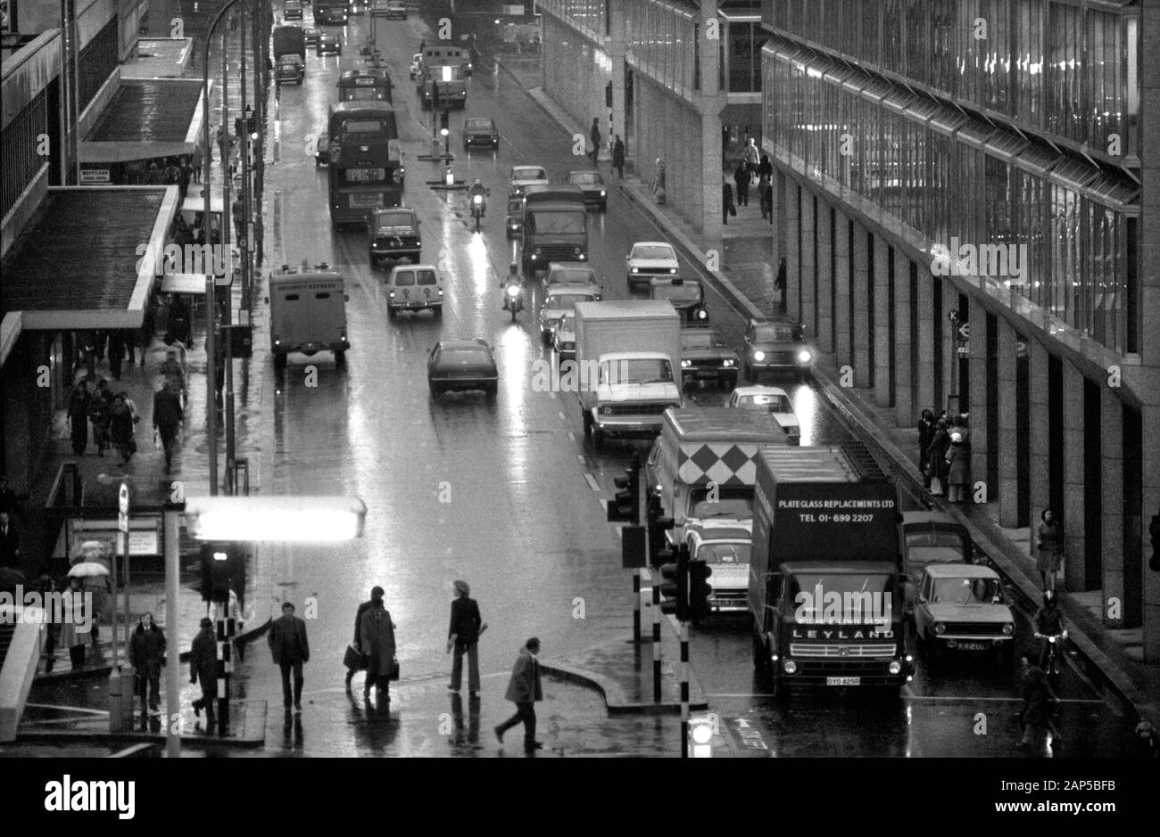 London 1970s Victoria Street. Ora di punta serale, persone, taxi, auto e autobus scuri e bagnati come pendolari fare il loro modo di casa. 1976 UK HOMER SYKES Foto Stock