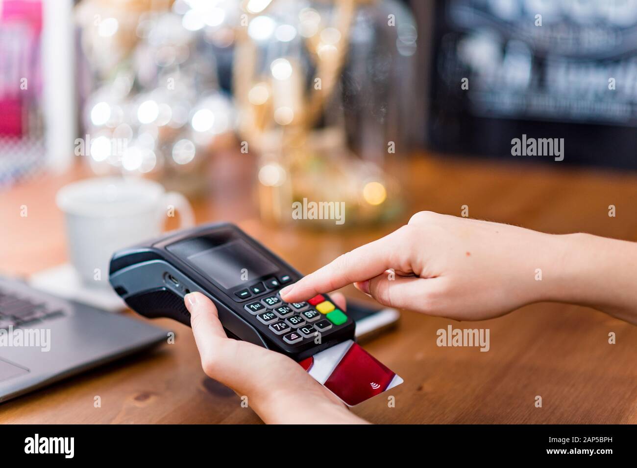 Vista ritagliata della mano che inserisce il codice PIN sicuro sul terminale per pagare l'acquisto con carta di credito. Pagamento senza contanti Foto Stock