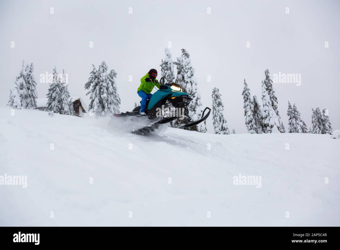 Uomo avventuroso in sella ad una motoslitta nel bianco della neve Foto Stock