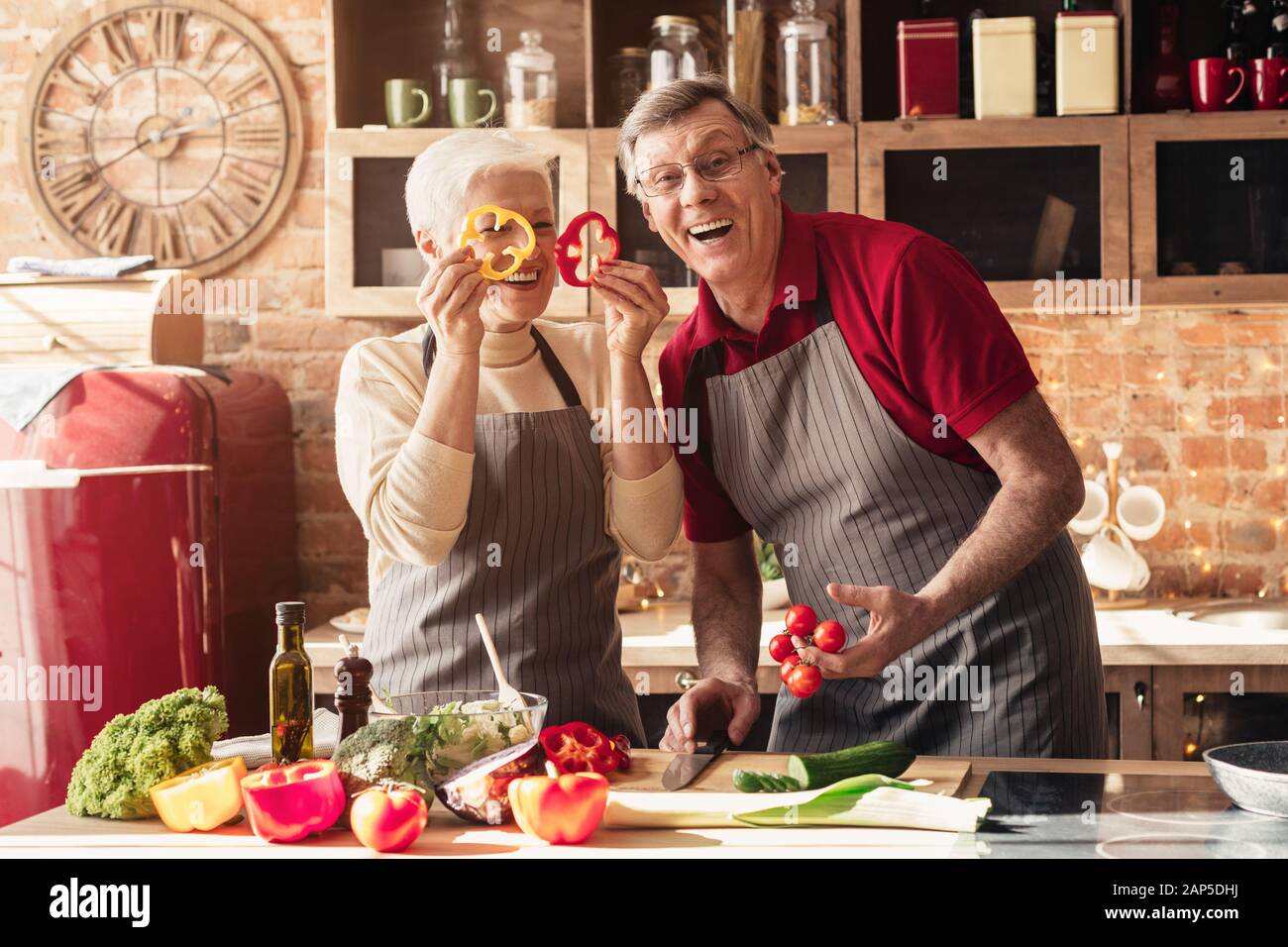 Coppia senior che gioca con verdure fresche in cucina Foto Stock