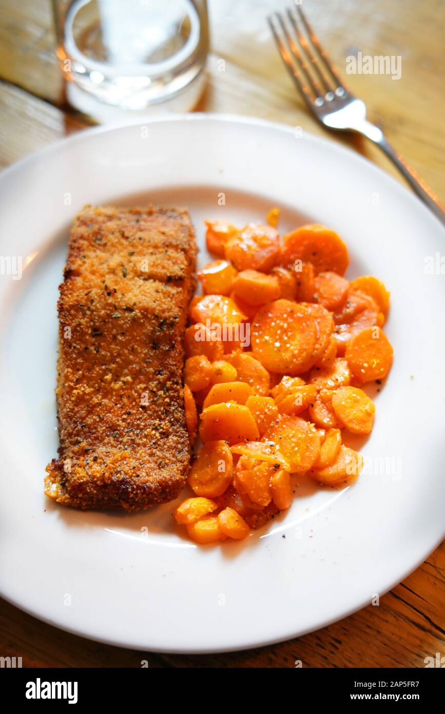 Filetto di salmone cotto in una crosta di pane e le carote affettate rosolate in una padella, Italia, Europa Foto Stock