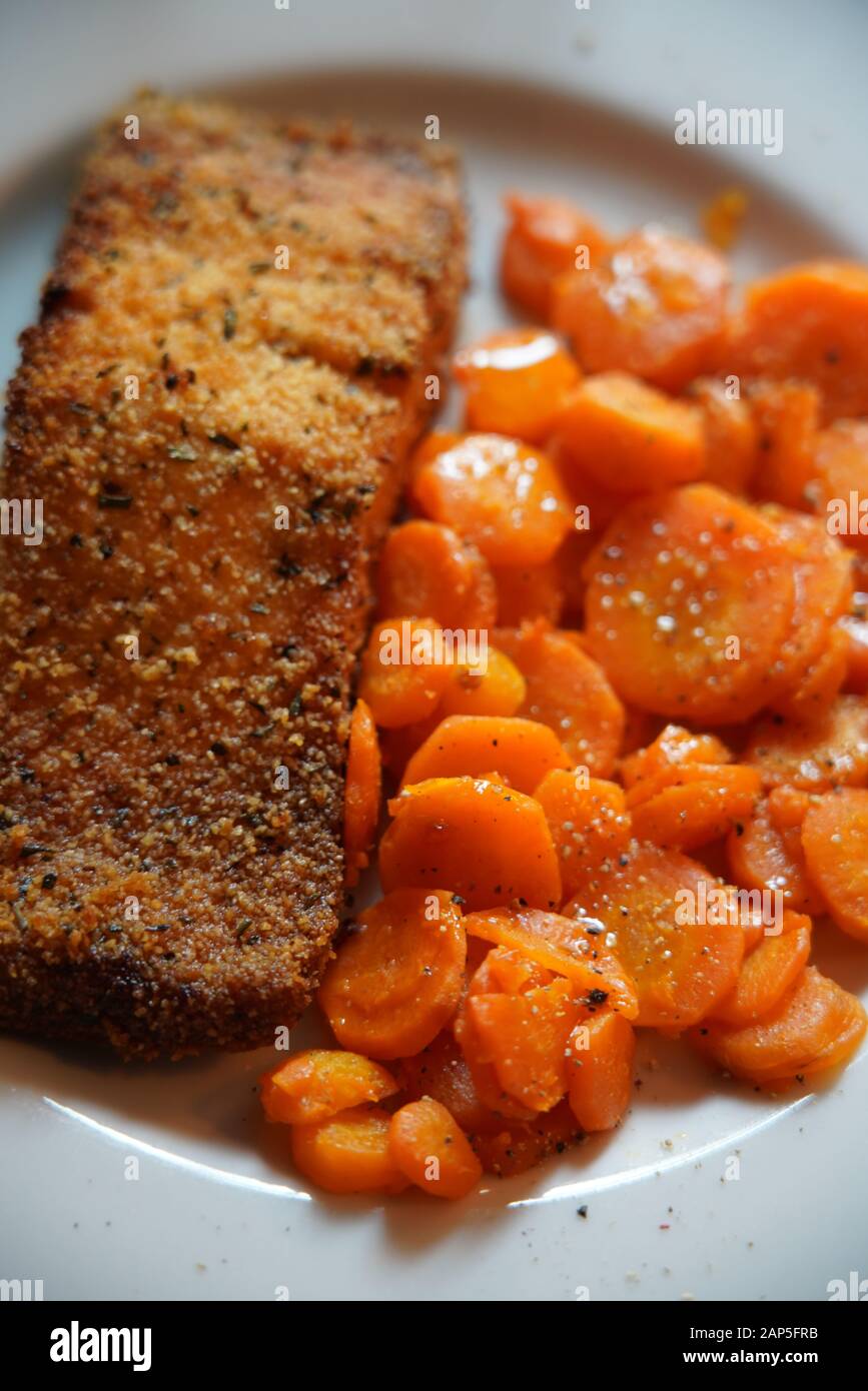 Filetto di salmone cotto in una crosta di pane e le carote affettate rosolate in una padella, Italia, Europa Foto Stock