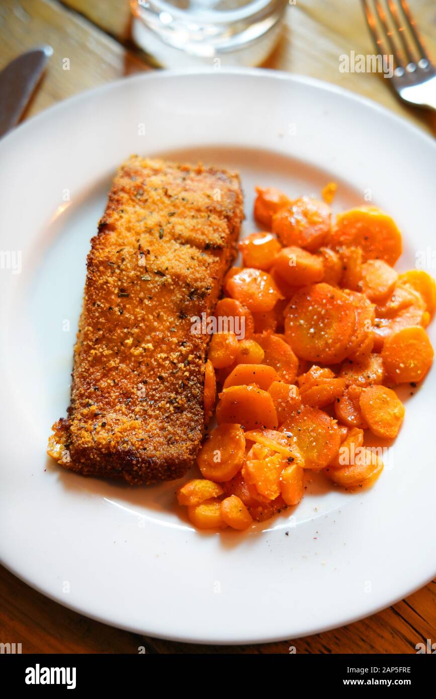 Filetto di salmone cotto in una crosta di pane e le carote affettate rosolate in una padella, Italia, Europa Foto Stock