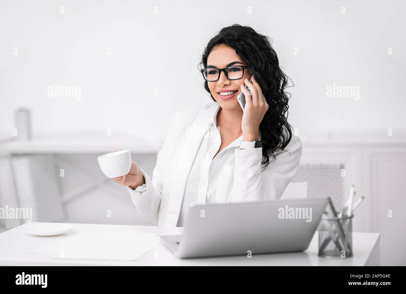 Donna d'affari ispanica sorridente che parla sul suo cellulare Foto Stock