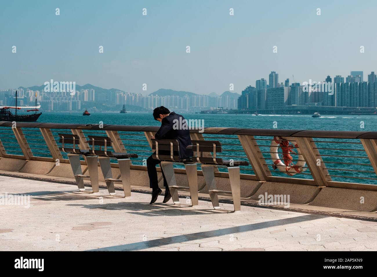 Uomo che guarda un telefono cellulare all'aperto con lo sfondo dello skyline di Hong Kong Foto Stock