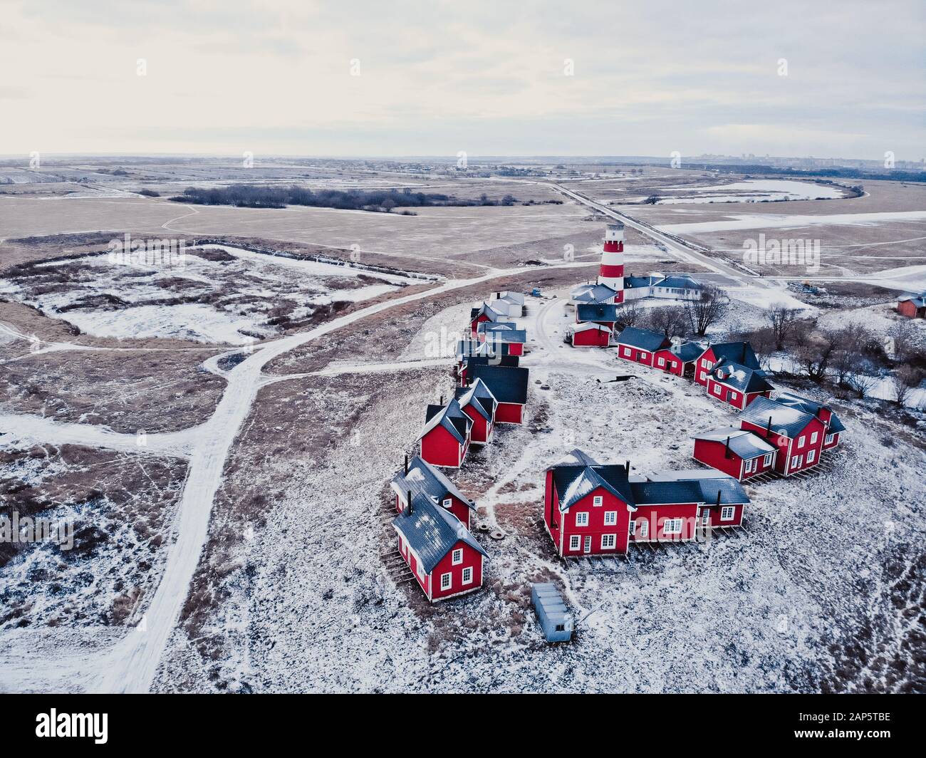 Case rosse di legno del villaggio di pescatori in nevoso coperto in inverno. Elegante e moderno villaggio di pescatori da una vista a volo d'uccello. Alcune case rosse vicino al Foto Stock