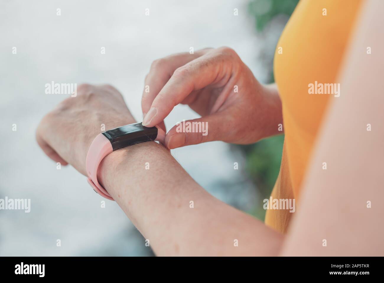 Donna escursionista utilizzando smart con la fascetta da polso durante il trekking in natura. Close up di mani femminili con orologio fitness, il fuoco selettivo. Foto Stock