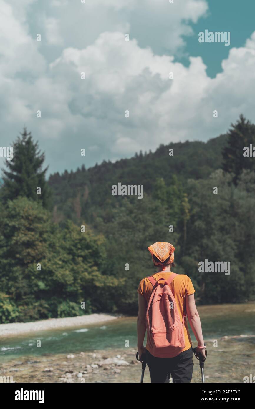 Vista posteriore di un escursionista femmina godendo di vista del fiume di montagna mentre trekking nella foresta durante la vacanza attiva vacanza Foto Stock