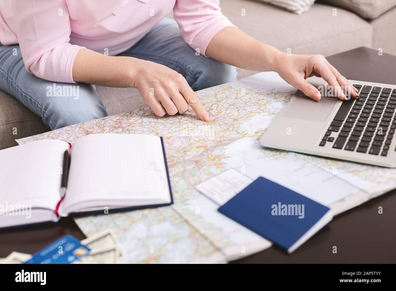 Donna anziana scelta viaggio sulla mappa, prenotazione hotel su computer portatile Foto Stock