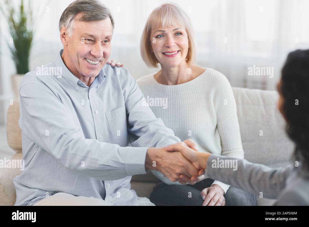 Coppia matura felice che dà al medico una stretta di mano Foto Stock