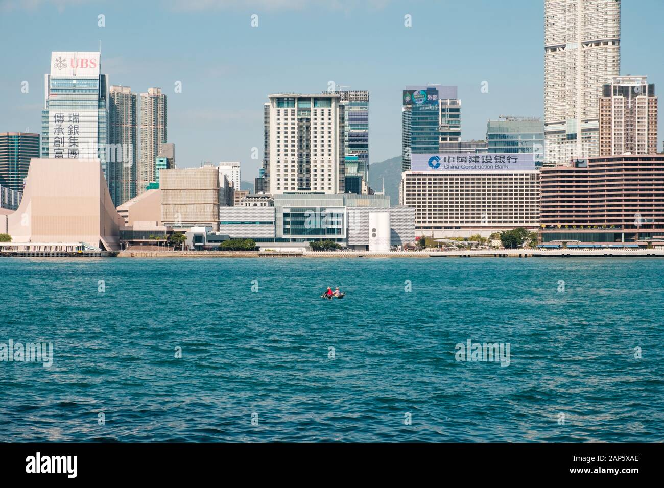 Hong Kong Cina - Novembre 2019: piccola barca sul Victoria Harbour con Skyline e la vista della costa di Hong Kong e Kowloon e Tsim Sha Tsui Foto Stock