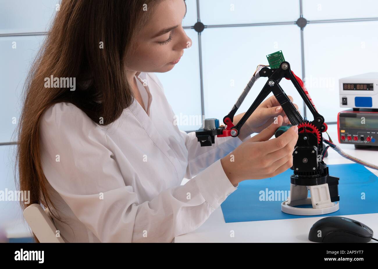 Donna studente con robot industriale braccio nel laboratorio di progettazione Foto Stock